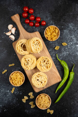 Noodle rolls with green chilies, cherry tomatoes and garlic on a wooden board