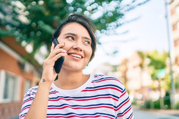 Young latin girl smiling happy talking on the smartphone at the city