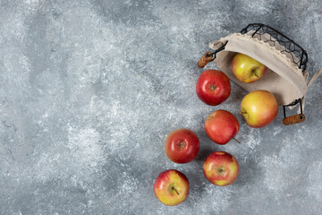 Pile of fresh ripe apples out of wicker basket on marble surface