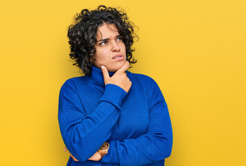 Fototapeta na wymiar Young hispanic woman with curly hair wearing turtleneck sweater thinking worried about a question, concerned and nervous with hand on chin