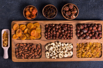 Dried fruits and nut mix on wooden board, top view. Healthy snack