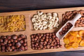 Dried fruits and nut mix on wooden board, top view. Healthy snack
