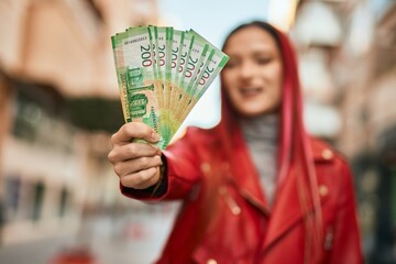 Young caucasian girl smiling happy holding russian ruble banknotes at the city.