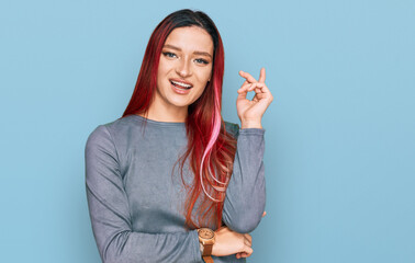 Young caucasian woman wearing casual clothes with a big smile on face, pointing with hand and finger to the side looking at the camera.