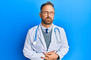 Handsome middle age man wearing doctor uniform and stethoscope with hand on stomach because indigestion, painful illness feeling unwell. ache concept.