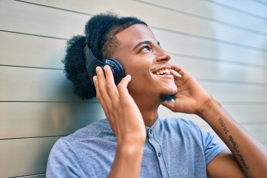 Young african american man listening to music using headphones at the city.