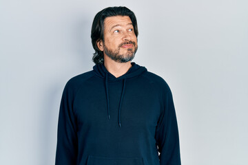 Middle age caucasian man wearing casual sweatshirt smiling looking to the side and staring away thinking.
