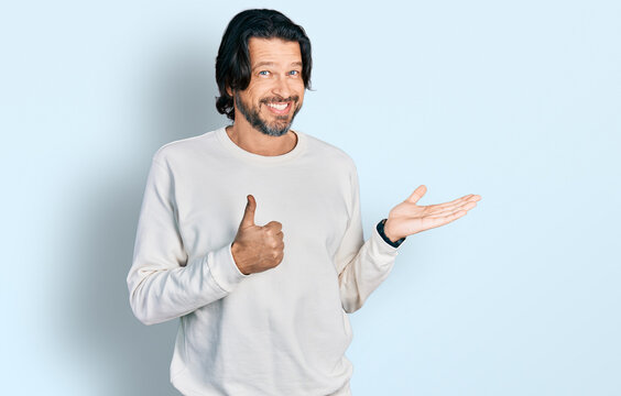 Middle age caucasian man wearing casual clothes showing palm hand and doing ok gesture with thumbs up, smiling happy and cheerful