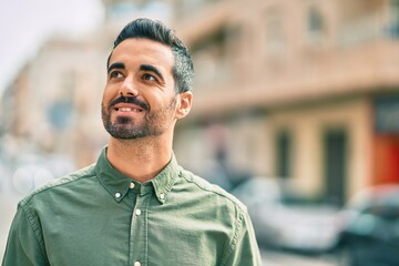 Young hispanic man smiling happy standing at the city.