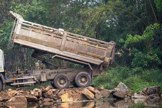 The truck was pouring rocks to fill the river.