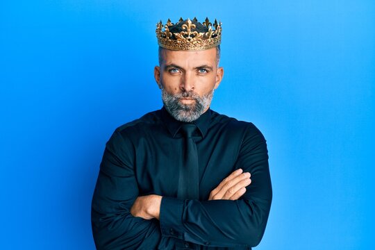 Middle age handsome business man wearing king crown skeptic and nervous, disapproving expression on face with crossed arms. negative person.