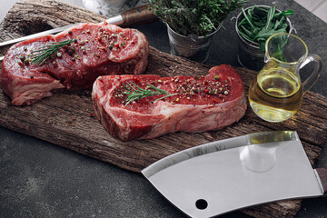 fresh raw striploin steak on a wooden board on a wooden background with salt and pepper in a rustic style.