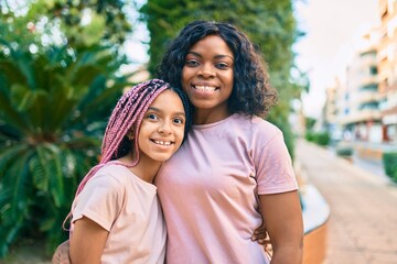 Obraz premium Beautiful african american mother and daughter smiling happy and hugging. Standing with smile on face standing at the park.