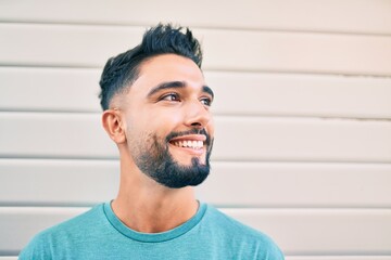 Young arab man smiling happy leaning on the wall at the city.