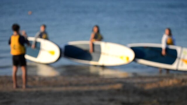 Blurred background. Many people standing on sea and take pictures with sup board