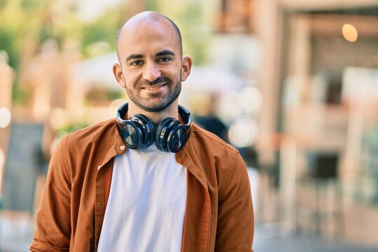 Young hispanic bald man smiling happy using headphones at the city