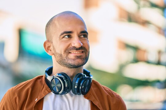 Young hispanic bald man smiling happy using headphones at the city
