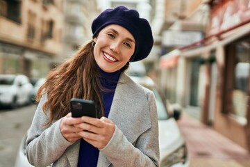 Young blonde woman smiling happy using smartphone at the city.