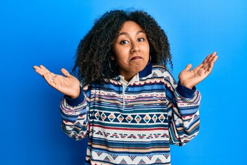 Beautiful african american woman with afro hair wearing casual clothes clueless and confused with...