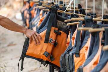 Many orange life jackets Hands holding life jackets