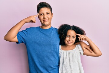 Young hispanic family of brother and sister wearing casual clothes together smiling pointing to head with one finger, great idea or thought, good memory