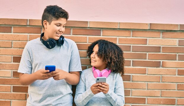 Adorable latin brother and sister smiling happy using smartphone at the city.