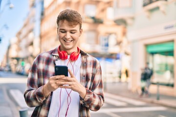 Young caucasian man smiling happy using smartphone at the city.