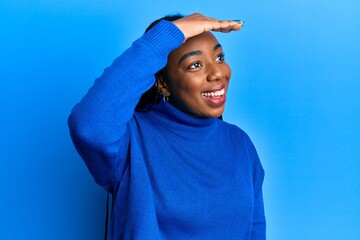 Young african american woman wearing casual winter sweater very happy and smiling looking far away...
