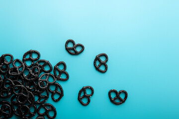 Mini black pretzels on light blue background