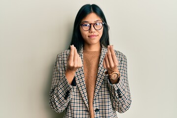 Young chinese woman wearing business style and glasses doing money gesture with hands, asking for salary payment, millionaire business