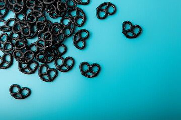 Mini black pretzels on light blue background
