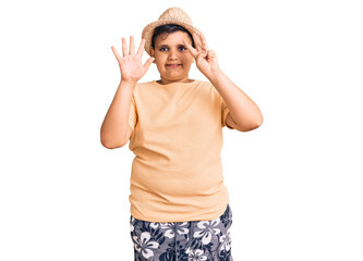 Little boy kid wearing summer hat and hawaiian swimsuit showing and pointing up with fingers number eight while smiling confident and happy.