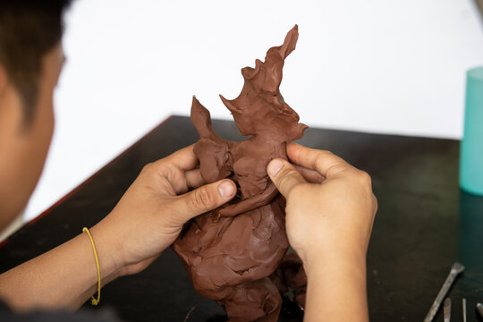 Close up of Sculptor artist creating The statue with clay.