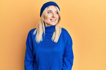 Young caucasian woman wearing wool winter sweater and cap looking to side, relax profile pose with natural face and confident smile.