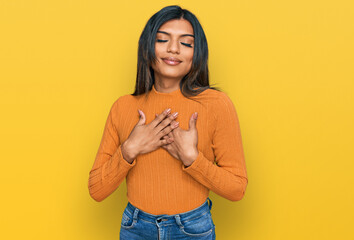 Young latin transsexual transgender woman wearing casual clothes smiling with hands on chest with closed eyes and grateful gesture on face. health concept. - obrazy, fototapety, plakaty