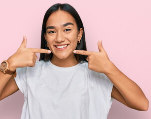 Young asian woman wearing casual white t shirt smiling cheerful showing and pointing with fingers teeth and mouth. dental health concept.