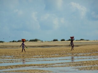 Fototapeta na wymiar [Madagascar] Two African women walking on a sandy beach after the tide (Betania village, Morondava)