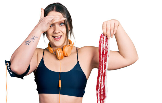 Young hispanic girl wearing sportswear holding meat stressed and frustrated with hand on head, surprised and angry face