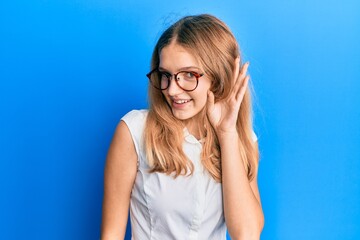 Naklejka premium Beautiful young caucasian girl wearing casual clothes and glasses smiling with hand over ear listening and hearing to rumor or gossip. deafness concept.