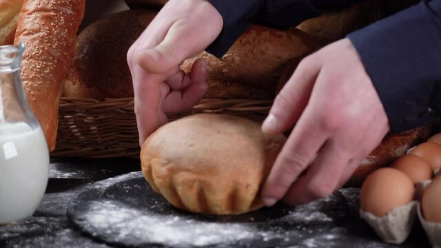 Still life sort of bread. An assortment of fresh organic breads on a vintage wooden surface. Male hand to lay down cornbread. Baking and healthy eating.