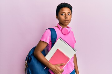 Young african american girl wearing school bag and holding books thinking attitude and sober...