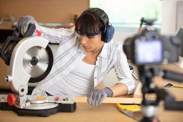 pretty female carpenter using electric sander for wood