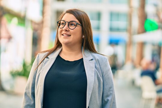 Young hispanic plus size businesswoman smiling happy standing at the city.
