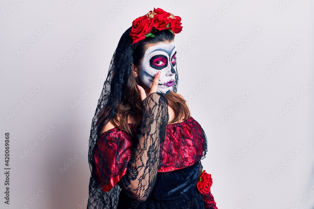 Poster young woman wearing day of the dead costume over white pointing to the eye watching you gesture, sus