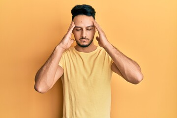Fototapeta na wymiar Young arab man wearing casual clothes suffering from headache desperate and stressed because pain and migraine. hands on head.