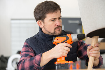 man repairing chair with drill