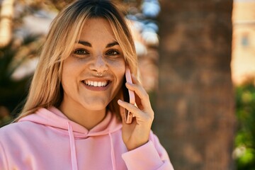 Young blonde sporty girl smiling happy talking on the smartphone at the city.