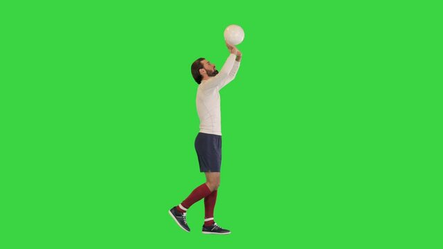 Football sportsman walking and bouncing a ball in hands like a volleyball ball on a Green Screen, Chroma Key.