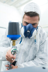 painter spraying paint on car to renew the varnish