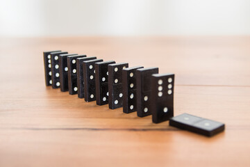 Black dominoes in a row standing on a wooden table